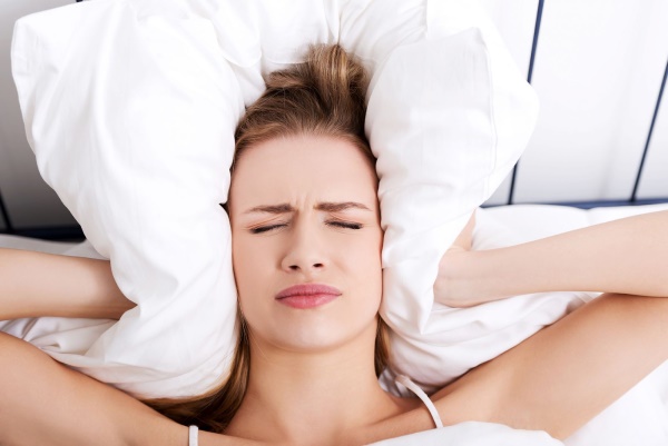 Woman holding Pillows over her ears to reduce sound